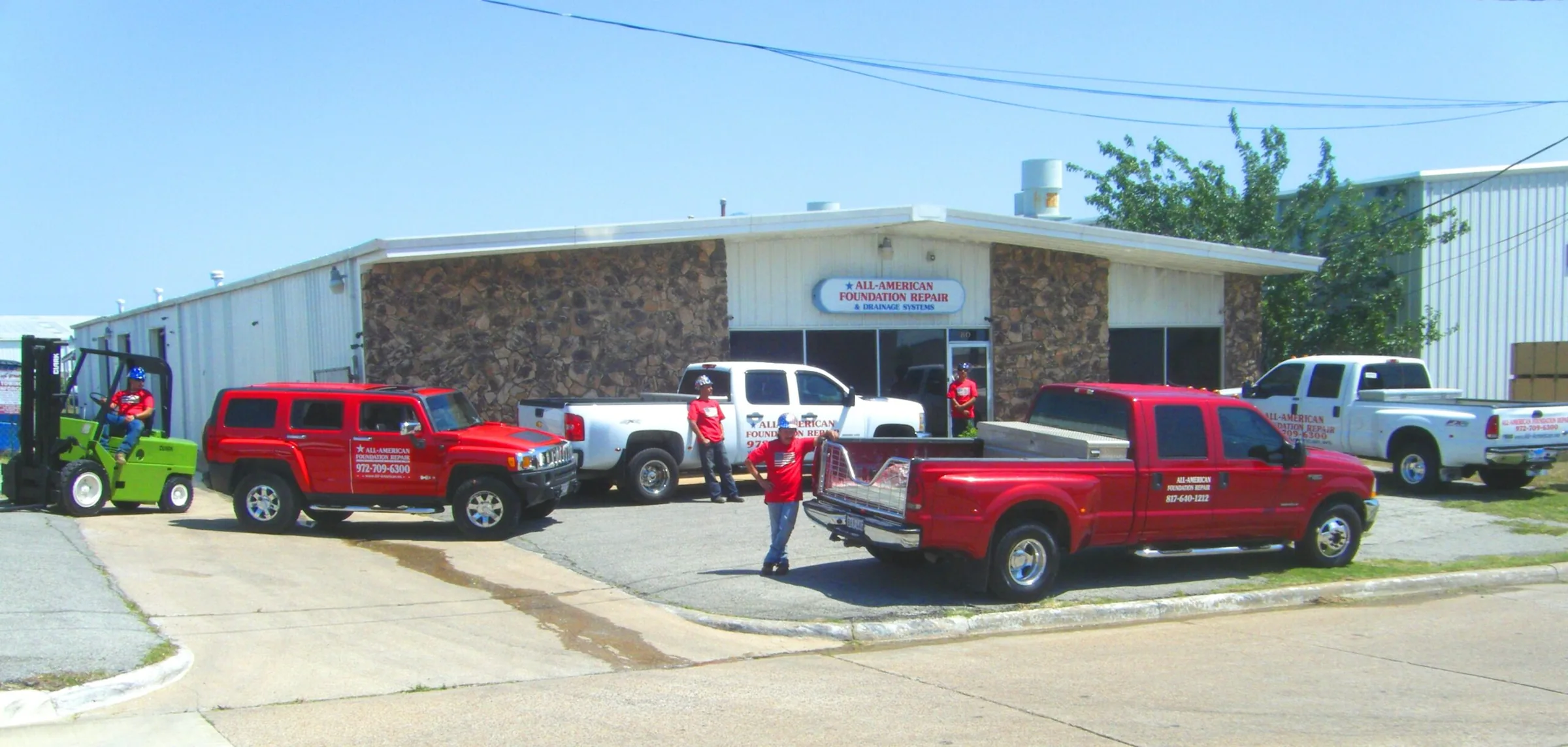 All American Foundation Repair storefront with red company vehicles and staff in front of building.
